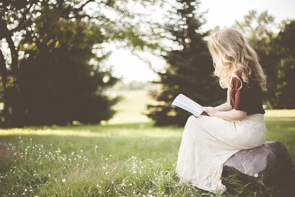 blonde girl reading in a field